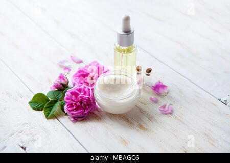 Spa Thema Objekte auf weißem Hintergrund Holz Spa mit Topf, feuchtigkeitsspendende Creme schöne rosa Rosen und rose Parfüm Öl Stockfoto