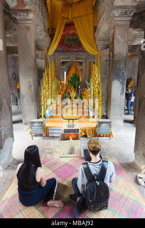 Tempel Angkor Wat Kambodscha - westlichen Touristen Paar brennende Räucherstäbchen vor einem Buddha Statue; Angkor Wat UNESCO Weltkulturerbe, Kambodscha Stockfoto