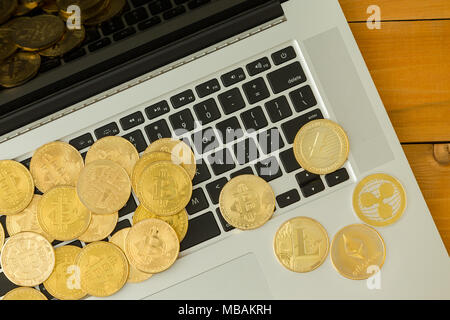 Goldene Münzen von cryptocurrencies, Bitcoin, des Astraleums und Litecoin, über Laptop Tastatur verstreut, gesehen von oben in Nahaufnahme Stockfoto