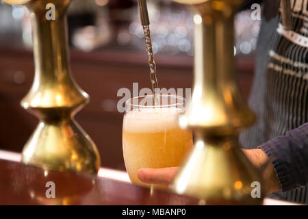 Nahaufnahme von einem Barkeeper Gießen eine blonde Bier in Tippen Stockfoto