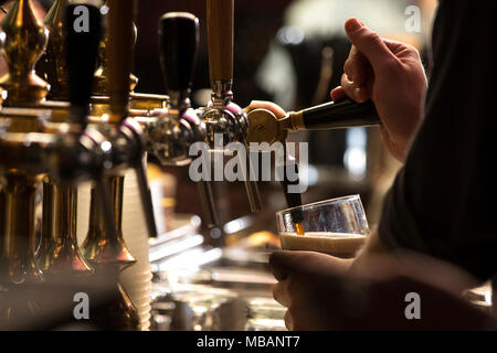 Nahaufnahme von einem Barkeeper gießen ein dunkles Stout Bier in mit Betreff und tippen Sie auf den richtigen Fokus Stockfoto