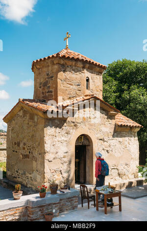 Mzcheta, Georgia. Die alten kleinen Stein Kirche St. Nina in der Gegend von Samtavro Klosteranlage mit der Pilgernden Frau, die in der Nähe seines Entran Stockfoto