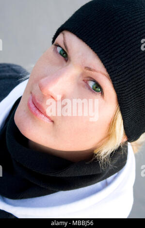 Portrait der Grünäugige Blondine in Schwarz in Mütze und Schal Stockfoto