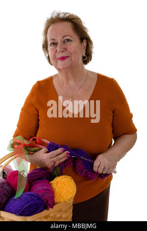 Portrait der älteren Frau, die mit Stricken Zubehör gegen den weißen Hintergrund Stockfoto