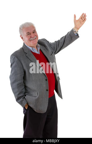 Entspannt lächelnd glücklich älterer Mann mit angehobenem Arm und andere in der Hand in der Hosentasche drehen in die Kamera zu lächeln, als er ihr verweist auf etwas, was ich Stockfoto