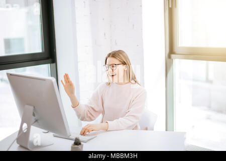 Business Frau an ihrem Arbeitsplatz sitzen und in video chat mit Freund Stockfoto