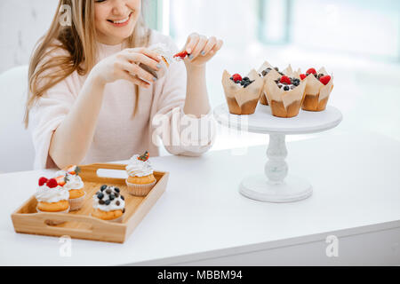 7/8-Ansicht von glücklichen jungen Frau cupcakes Essen Stockfoto