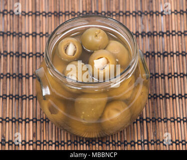Grüne kolossale Oliven gefüllt mit Knoblauch Handschuhe Hand in den jar Stockfoto