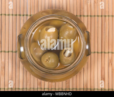 Grüne kolossale Oliven gefüllt mit Knoblauch Handschuhe Hand in den jar Stockfoto