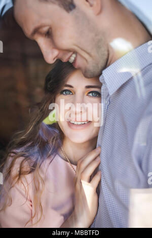 Junges Paar lächelnd umarmen in der Nähe der Fenster Stockfoto