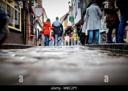 Tief unten geschossen von Menschen und Paar Hände halten einen alten traditionellen gepflasterten Englisch Straße während dem Surfen durch Geschäfte auf dem Einzelhandel Therapie Tag Stockfoto