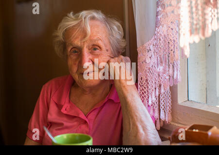 Eine ältere Frau sitzt am Küchentisch. Stockfoto
