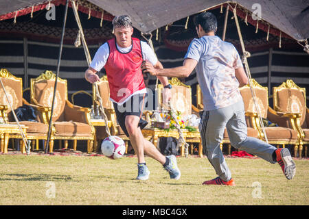 Us Air Force Brig. Gen. Jason R. Armagost, Kommandant der 379 Air Expeditionary Wing, spielt Fußball mit Qatar Air Force des Emirs und USAF Führung während Qatar National Sport Tag im Al Udeid Air Base, Katar, 13.02.2018. Wettbewerber an mehreren Veranstaltungen während des ganzen Tages wie Volleyball, Fußball, Basketball und Schiene. Der Urlaub begann 2011 nach Emir Scheich Tamim Bin Hamad Al Thani die Ferien zu einem gesunden und aktiven Lebensstil zu fördern. (U.S. Air National Guard Stockfoto