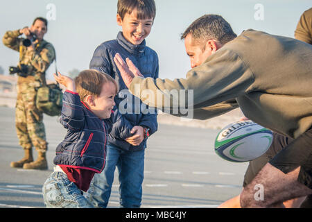 Ein Mitglied der britischen Royal Air Force zu 83 Expeditionary Luft Gruppe zugeordnet, gibt einem Kind einen hohen - fünf während Qatar National Sport Tag im Al Udeid Air Base, Katar, 13.02.2018. Wettbewerber an mehreren Veranstaltungen während des ganzen Tages wie Volleyball, Fußball, Basketball und Schiene. Der Urlaub begann 2011 nach Emir Scheich Tamim Bin Hamad Al Thani die Ferien zu einem gesunden und aktiven Lebensstil zu fördern. (U.S. Air National Guard Stockfoto