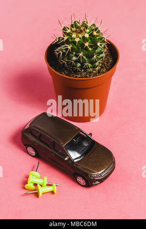 Closeup Kaktus in Braun Vase mit Modell Auto auf Rosa Backgrounf. Bild für Natur, Niemand, Sommer, Garten Konzept. Stockfoto