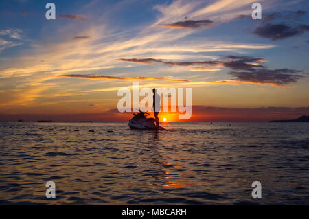 Silhouette eines Mannes auf einem Jet-ski in der Sonne auf dem Meer Sonnenuntergang im Sommer Abend Stockfoto