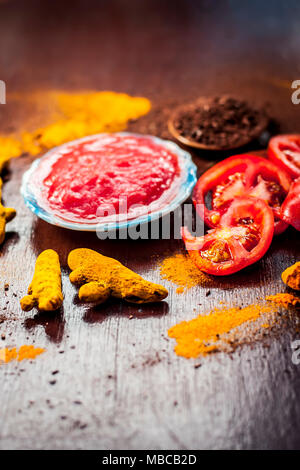 Nahaufnahme von Tomatenmark, Sandelholz, Kurkuma und seine Pulver auf einer hölzernen Oberfläche. Sie wird verwendet, um die dunklen Köpfe und schwarze Haut zu löschen. Stockfoto