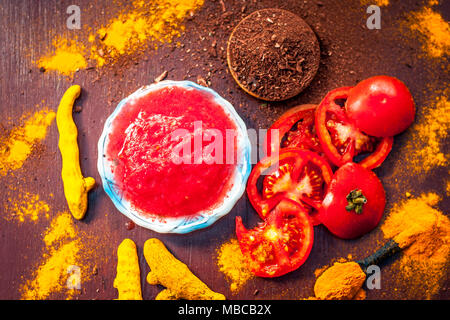 Nahaufnahme von Tomatenmark, Sandelholz, Kurkuma und seine Pulver auf einer hölzernen Oberfläche. Sie wird verwendet, um die dunklen Köpfe und schwarze Haut zu löschen. Stockfoto