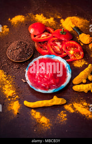 Nahaufnahme von Tomatenmark, Sandelholz, Kurkuma und seine Pulver auf einer hölzernen Oberfläche. Sie wird verwendet, um die dunklen Köpfe und schwarze Haut zu löschen. Stockfoto