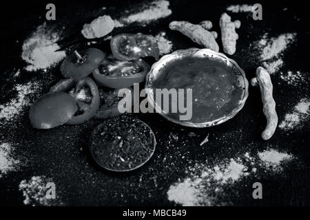 Nahaufnahme von Tomatenmark, Sandelholz, Kurkuma und seine Pulver auf einer hölzernen Oberfläche. Sie wird verwendet, um die dunklen Köpfe und schwarze Haut zu löschen. Stockfoto