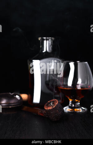 Glas Whiskey mit Rauchen Zigarre auf dunklen Holztisch Stockfoto