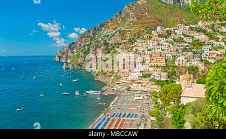 Schöne Panoramasicht auf Häuser, den Strand und die Berge in Positano an sonnigen Sommertagen, Salerno, Kampanien, Italien Stockfoto