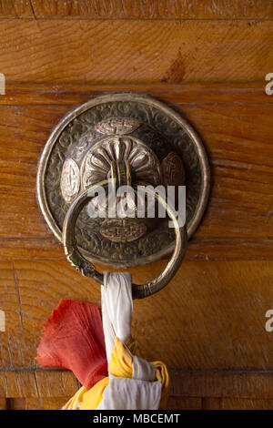 Schwere und verzierten, dieses einzigartige Messing Türklopfer in Likir buddhistische Kloster in der Nähe von Leh im Norden von Indien hat weißen, roten und gelben Bändern befestigt. Stockfoto