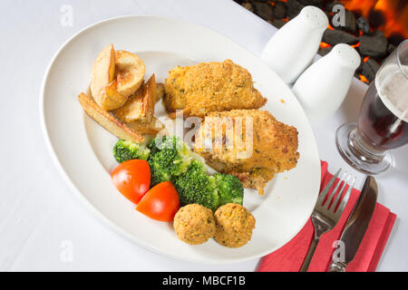 Ein englisches Pub/Restaurant Teller Golden gebratene panierte Hühnerkeule mit Kartoffelecken serviert, Brokkoli und Füllung Kugeln Stockfoto