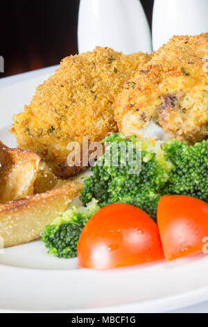 Ein englisches Pub/Restaurant Teller Golden gebratene panierte Hühnerkeule mit Kartoffelecken serviert, Brokkoli und Füllung Kugeln Stockfoto