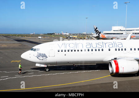 Das Bodenpersonal Regie eine Jungfrau Australien Boeing 737-800 auf der Rollbahn am Flughafen Sydney, Domestic Terminal, Australien Stockfoto