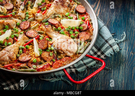 Traditionelle Paella mit Huhn Beine, Chorizo Wurst und Gemüse in paellera serviert. Spanische Küche Stockfoto