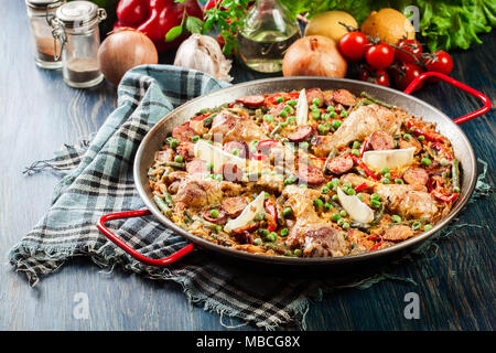 Traditionelle Paella mit Huhn Beine, Chorizo Wurst und Gemüse in paellera serviert. Spanische Küche Stockfoto