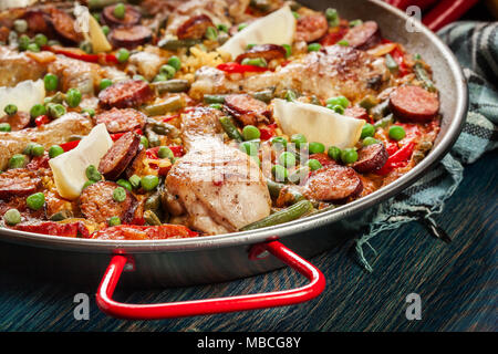 Traditionelle Paella mit Huhn Beine, Chorizo Wurst und Gemüse in paellera serviert. Spanische Küche Stockfoto