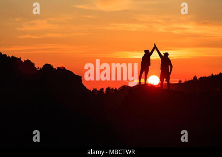 Teamwork Paar feiern Silhouette in inspirierende Berge Sonnenuntergang. Team der Kletterer feiern erreicht Ziel und Erfolg. Leistung und Motivation Stockfoto