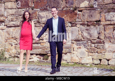 Elegante lächelndes Paar mit schwangeren Frau in den 30er Jahren Hand in Hand. Stockfoto