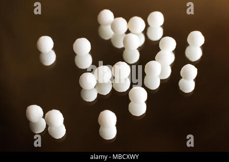 Homöopathische Kugeln auf dem Spiegel Hintergrund verstreut. Close-up. Stockfoto