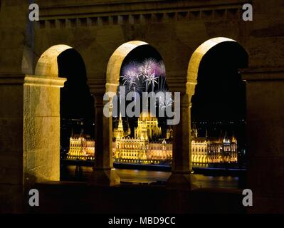 Ungarisches Parlament durch Fischerhochburg Arkaden, mit Feuerwerk, Budapest. Stockfoto