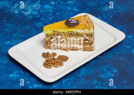 Stück Karotte Kuchen mit Puderzucker und Walnuss auf weiße Platte, blauen Hintergrund, Nahaufnahme Stockfoto