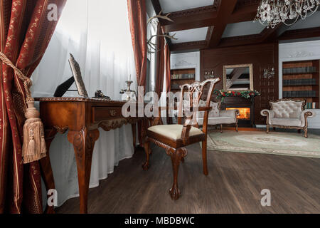 Alte Studium Zimmer mit Sessel, Textil und Holz- Tabelle. Klassische Bücherschrank gefüllt. Kamin Stockfoto