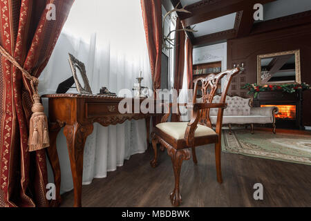 Alte Studium Zimmer mit Sessel, Textil und Holz- Tabelle. Klassische Bücherschrank gefüllt. Kamin Stockfoto