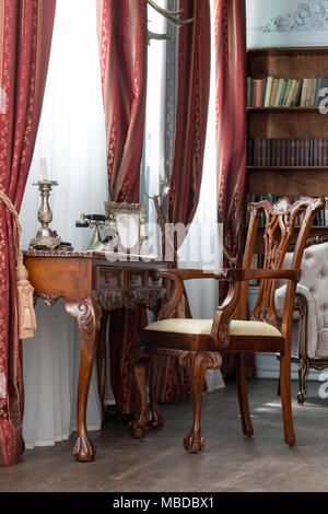 Alte Studium Zimmer mit Sessel, Textil und Holz- Tabelle. Klassische Bücherschrank gefüllt. Kamin Stockfoto