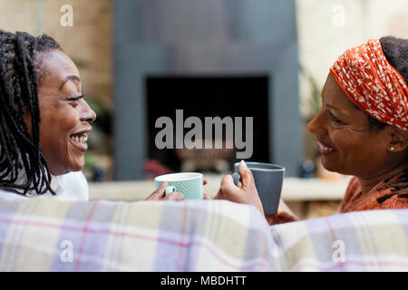 Lächelnde Frauen Freunde reden und Trinken von Tee auf dem Sofa Stockfoto