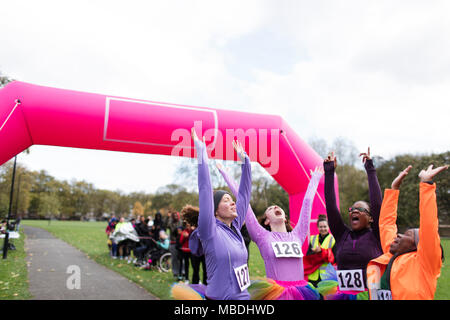 Begeisterte Läuferinnen mit tütü Jubeln, Feiern im spendenlauf Finish Line Stockfoto