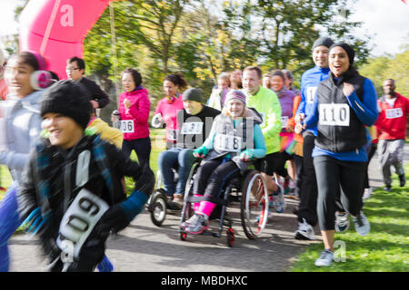 Läufer und Rollstuhlfahrer an der Nächstenliebe laufen im Park Stockfoto