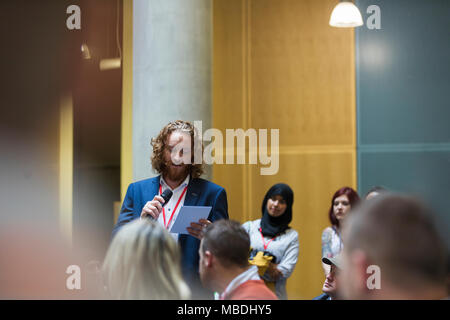 Geschäftsmann mit Mikrofon und Notizen Gespräch mit Publikum Stockfoto