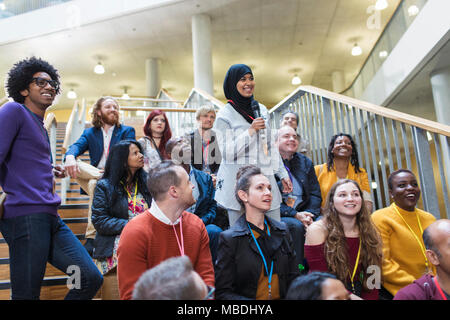 Lächelnde Frau im hijab im Gespräch mit Mikrofon in Konferenz Publikum Stockfoto