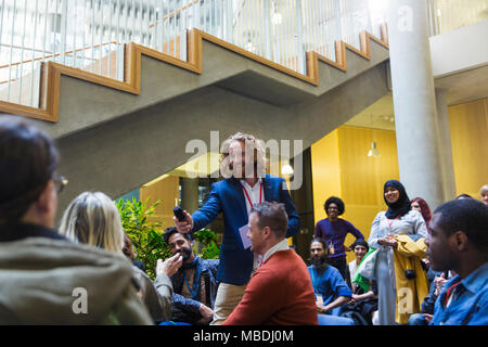 Lächelnd Sprecher männlich, Mikrofon zu Frau im Publikum Stockfoto