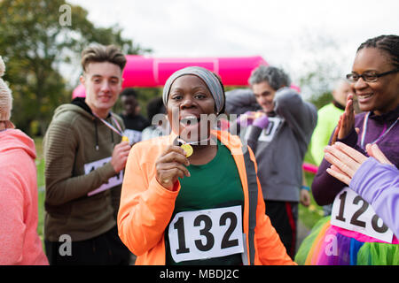 Portrait begeisterte Läuferin, die Medaille an Charity Run Stockfoto