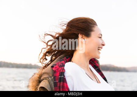 Lächelnd, unbekümmerte Frau am windigen Lakeside Stockfoto