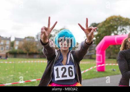 Portrait begeisterte Läuferin in Gestik, die Perücke friedenszeichen an der Nächstenliebe laufen im Park Stockfoto